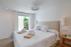 A hotel room with a large bed, white linens, a bedside table with a book and a plant, and a window with curtains. - El Jabeque 4 pax - Denia, Costa Blanca (Denia)