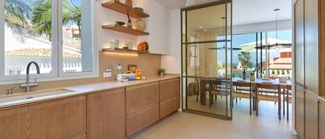A modern kitchen with wooden cabinets, a built-in oven, and a large window overlooking a patio area.
