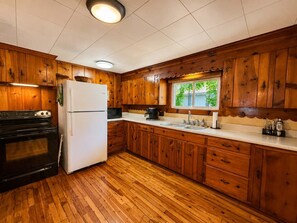A kitchen with wooden cabinets, a refrigerator, a stove, a microwave, and a sink. - Fish Tales Lake Days & Dock (Gravois Mills)