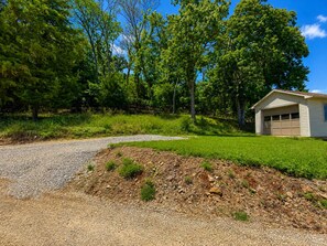 A residential property with a gravel driveway, a garage, and a lawn. - Fish Tales Lake Days & Dock (Gravois Mills)