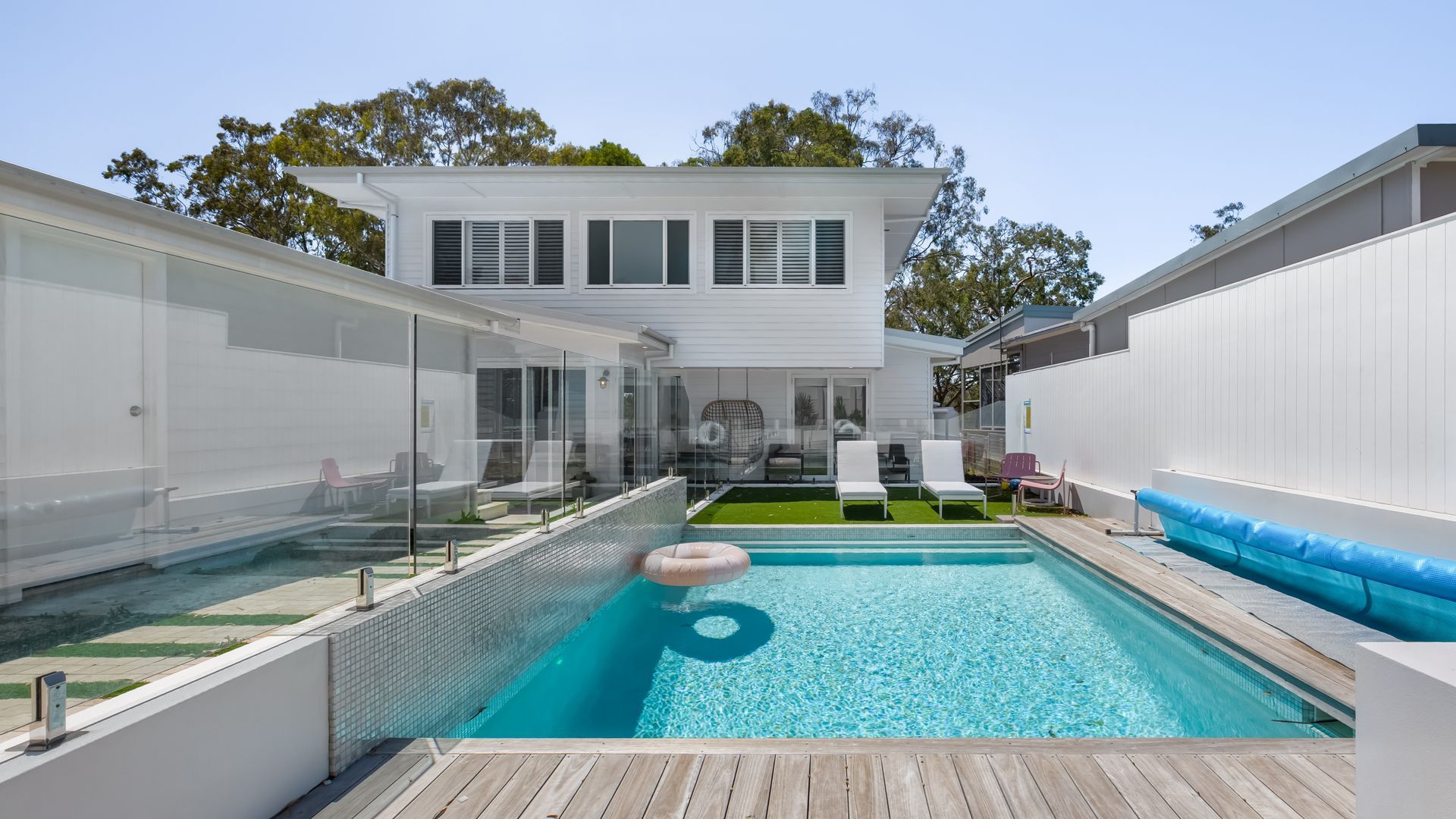 A modern pool area with a clear pool, lounge chairs, and a wooden deck.