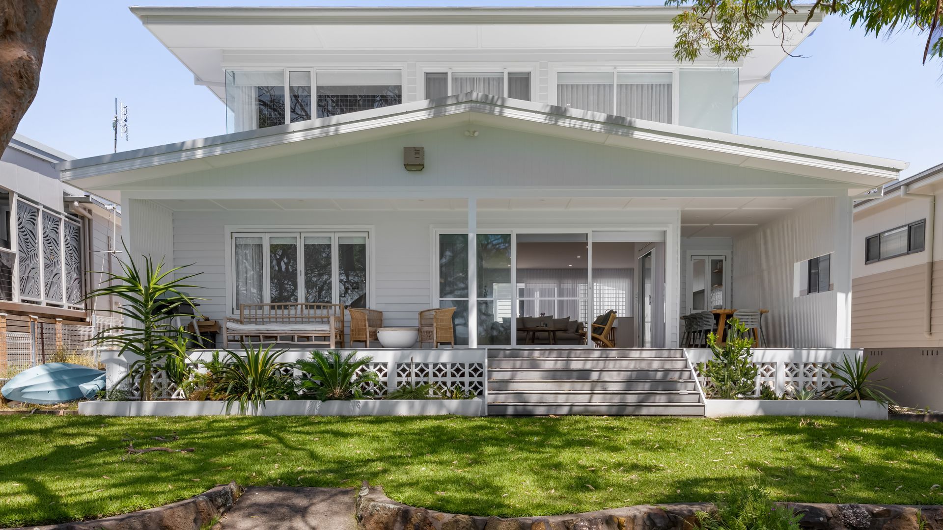 A two-story house with a covered porch, large windows, and a well-maintained lawn.