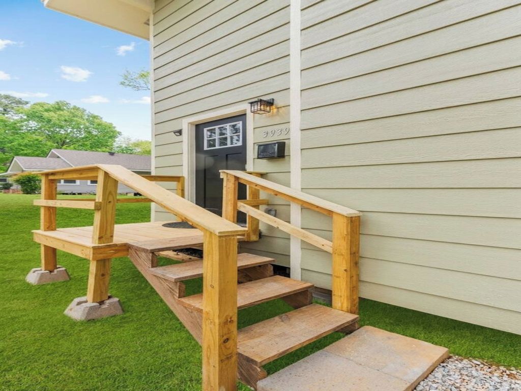 A wooden staircase leading to a house's front door with a mailbox above it.