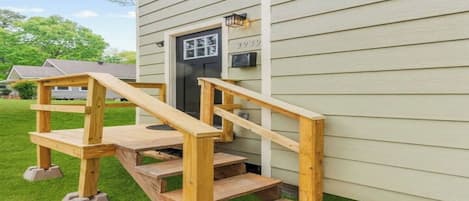 A wooden staircase leading to a house's front door with a mailbox above it.