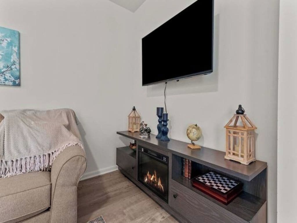 A living room with a flat-screen TV mounted on the wall, a fireplace, a sofa, and a console table with decorative items.