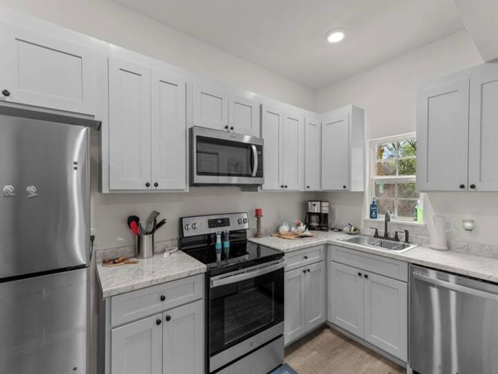 A modern kitchen with stainless steel appliances, white cabinetry, and a built-in microwave.
