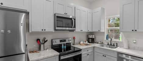 A modern kitchen with stainless steel appliances, white cabinetry, and a built-in microwave.