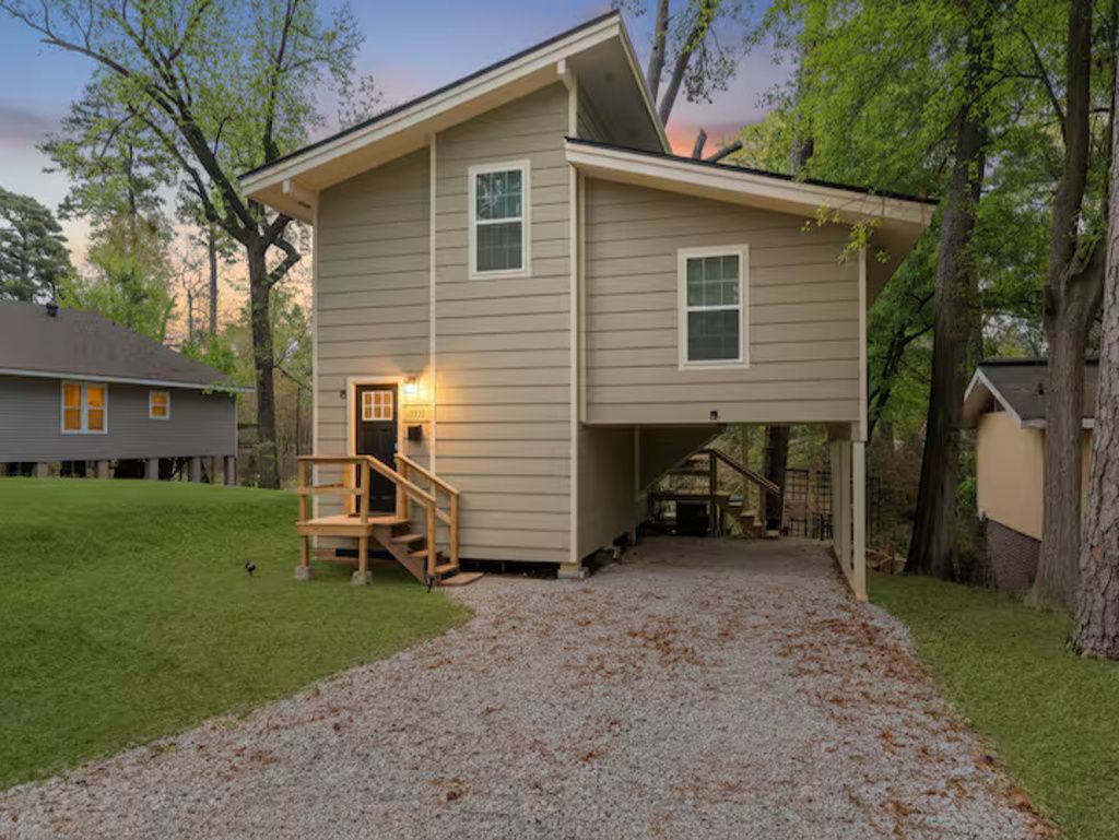 A two-story house with a covered porch and a gravel driveway.