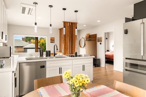 A modern kitchen with a central island, stainless steel appliances, and pendant lighting. - Private Softub, Walk to Junction - 2BR + Den, King Bed (Seattle)