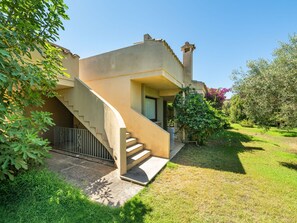A modern house with a curved staircase leading to a door, surrounded by lush greenery and a clear sky. - Vacation home Carlo by Interhome (Villasimius)