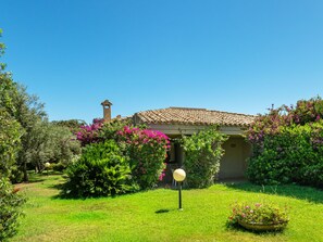 A villa with a tiled roof, surrounded by lush greenery and flowering plants. - Vacation home Carlo by Interhome (Villasimius)