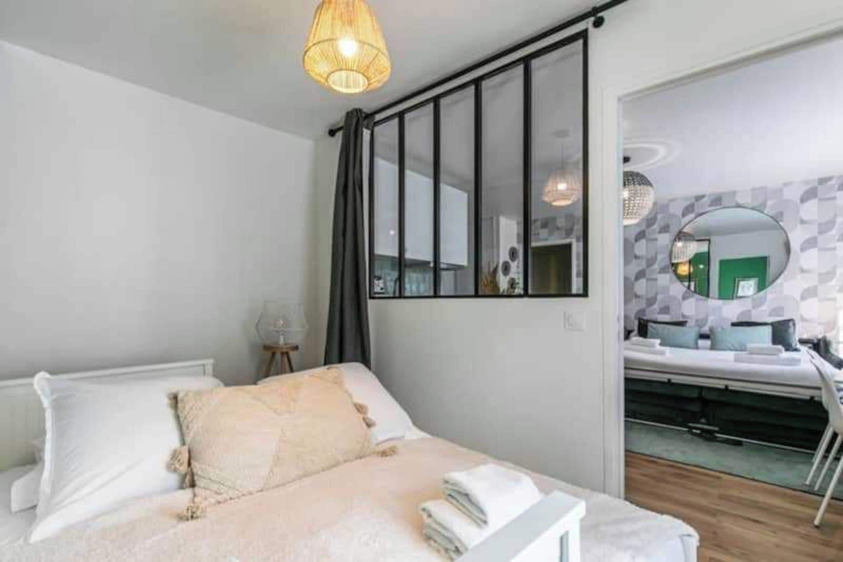 Ein Schlafzimmer mit einem Bett, einem großen Spiegel und Blick ins Bad.