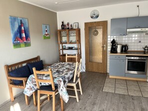 A cozy dining area with a wooden table and chairs, a wooden bench, and a wall with two paintings. - Holiday Apartment With 2 Bedrooms (Werdum)