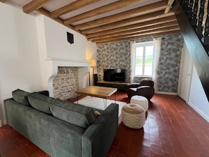 A living room with a stone fireplace, a television, a sofa, and a patterned wall.