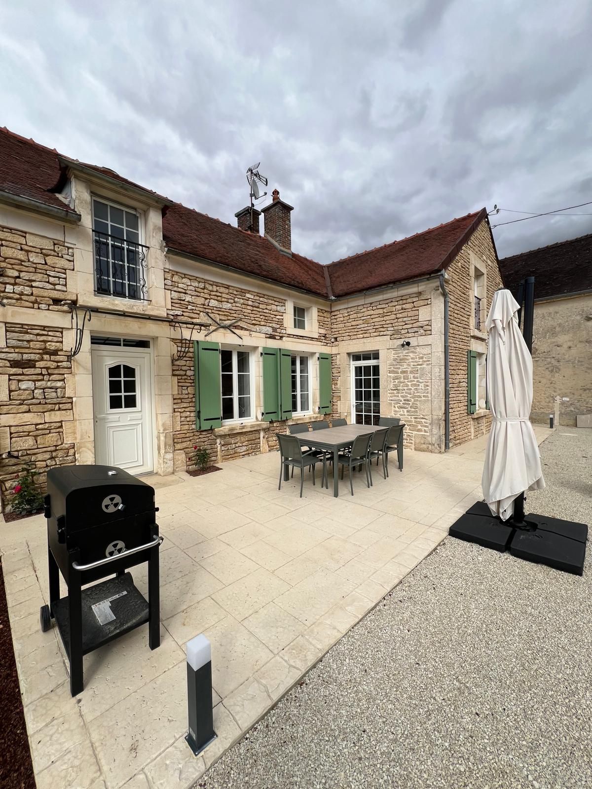 A stone building with a patio, outdoor seating, and a barbecue grill.