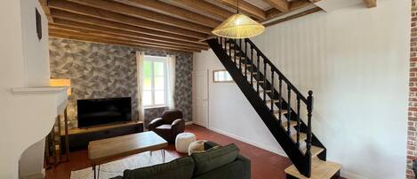 A living room with a sofa, a TV, a staircase, and a patterned wall.