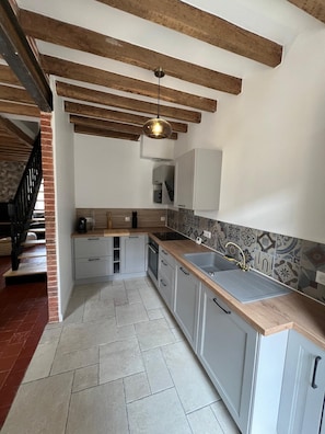 A modern kitchen with exposed wooden beams, a central island, and a patterned backsplash.