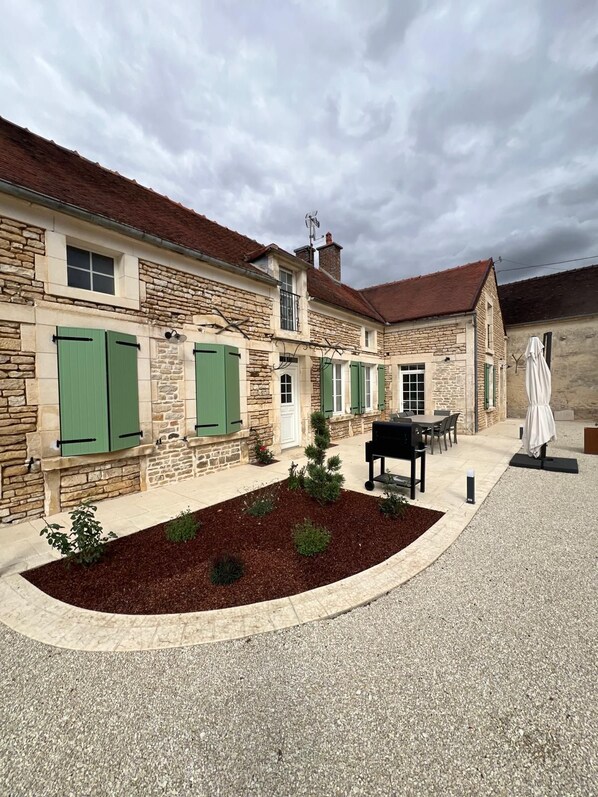 A stone building with a courtyard, outdoor seating, and a covered area.