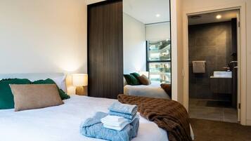 A hotel room with a bed, a mirror, a bathroom, and a view of the building's interior.
