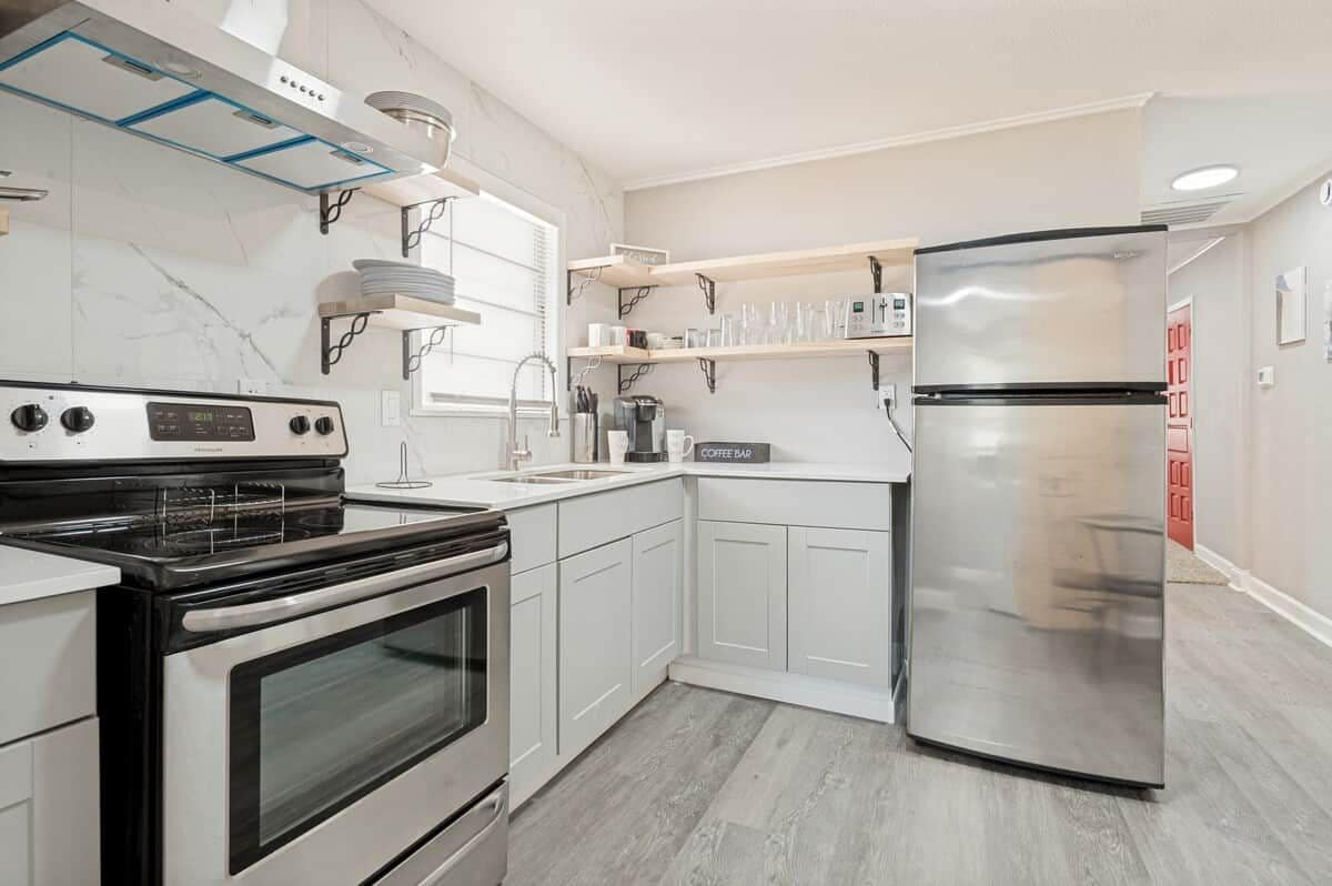 A modern kitchen with white cabinetry, a stainless steel refrigerator, and a built-in oven.