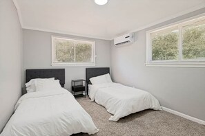 A bedroom with two beds, a window, and an air conditioning unit. - Lancaster Town Square House Near Downtown Dallas (Lancaster)