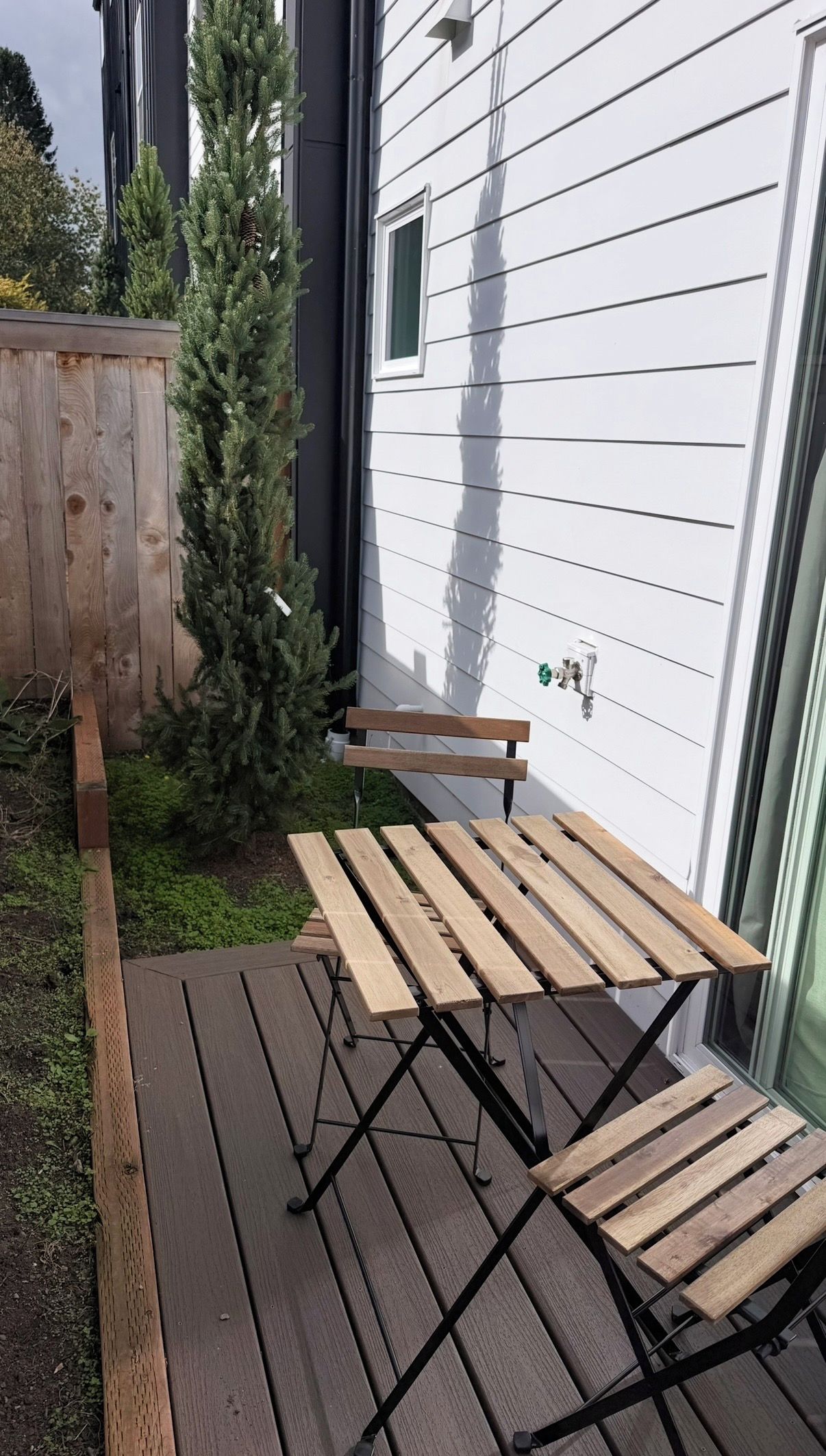 Una terraza de madera al aire libre con un banco y un pequeño árbol.
