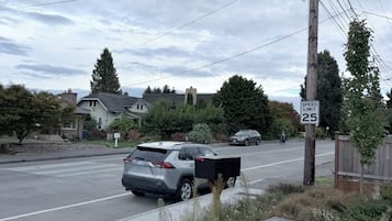 Una calle residencial con casas, una señal de límite de velocidad y un poste de servicios públicos.