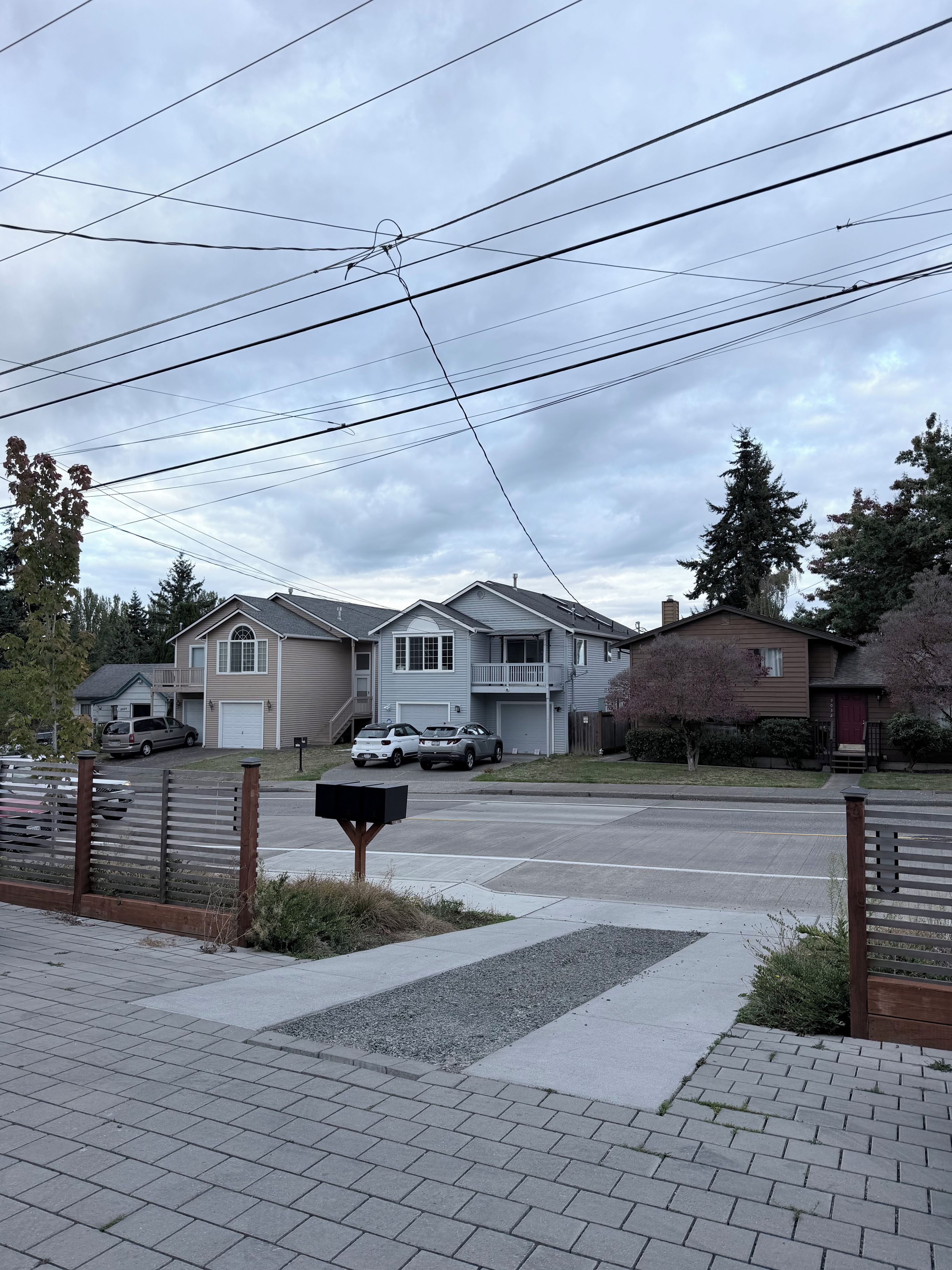 A residential street with houses, parked cars, and a mailbox.