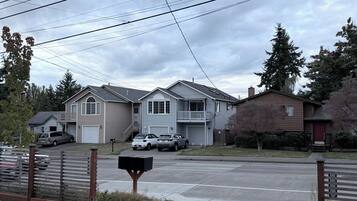 A residential street with houses, parked cars, and a mailbox.