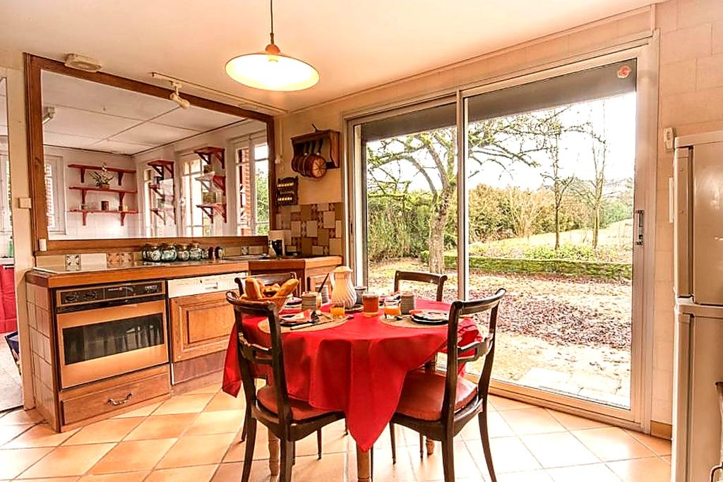 A kitchen with a dining table set for two, a large window, and a sliding glass door leading outside.
