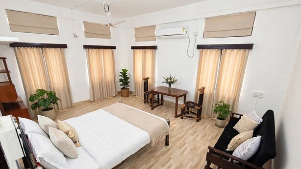 Une chambre d’hôtel avec un lit, un canapé, une table à manger et des plantes en pot.