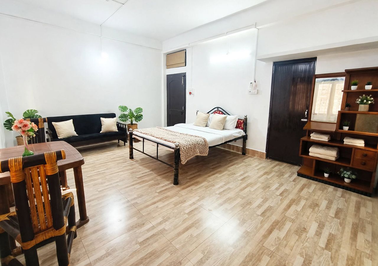 Ein Zimmer mit einem Bett, einem Schlafsofa, einem Esstisch und einer Holzkabine mit Pflanzen.