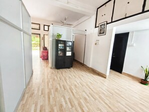 A hallway with a wooden floor, a black cabinet, and a ceiling fan.