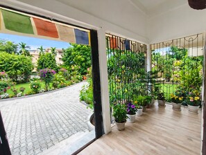 En balkon med plantekasser, udsigt til en have og en bygning i baggrunden.