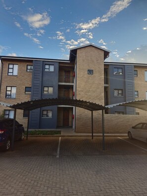 A multi-story residential building with a covered parking area.