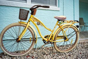 A yellow bicycle with a basket and a seat, parked on gravel. - Ormond Beach House Near the Shore (Ormond Beach)