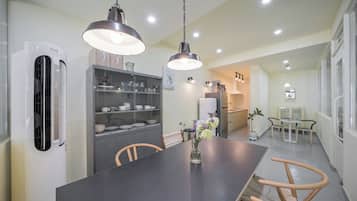 Cocina moderna con comedor, que incluye una isla central, iluminación colgante y un refrigerador.