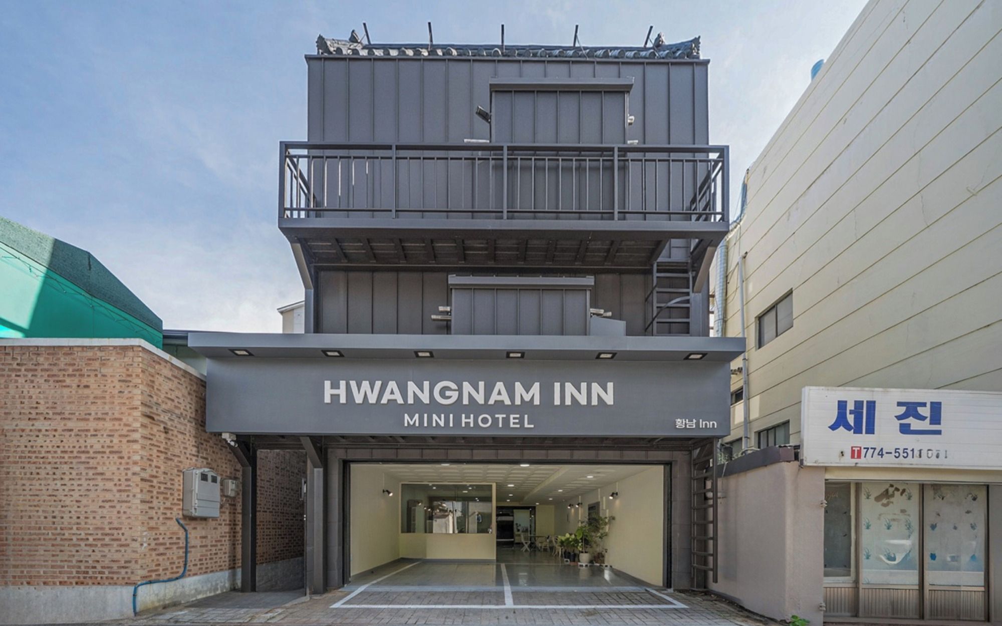 Un edificio de dos pisos con el letrero 'HWANGNAM INN MINI HOTEL' que indica un pequeño hotel.