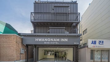 Un edificio de dos pisos con el letrero 'HWANGNAM INN MINI HOTEL' que indica un pequeño hotel.