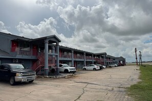 Un motel con varios pisos, estacionamiento al aire libre y cielo nublado.