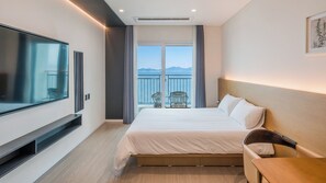 A hotel room with a bed, a TV, a balcony with a view of the sea, and a chair. - Yeongheungdo 36 Stay Pension (Incheon)