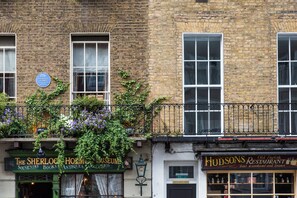 Ein Backsteinhaus mit grüner Markise, auf der die Schilder 'The Sherlock Holmes Museum' und 'Hudsons Restaurant' angebracht sind.
