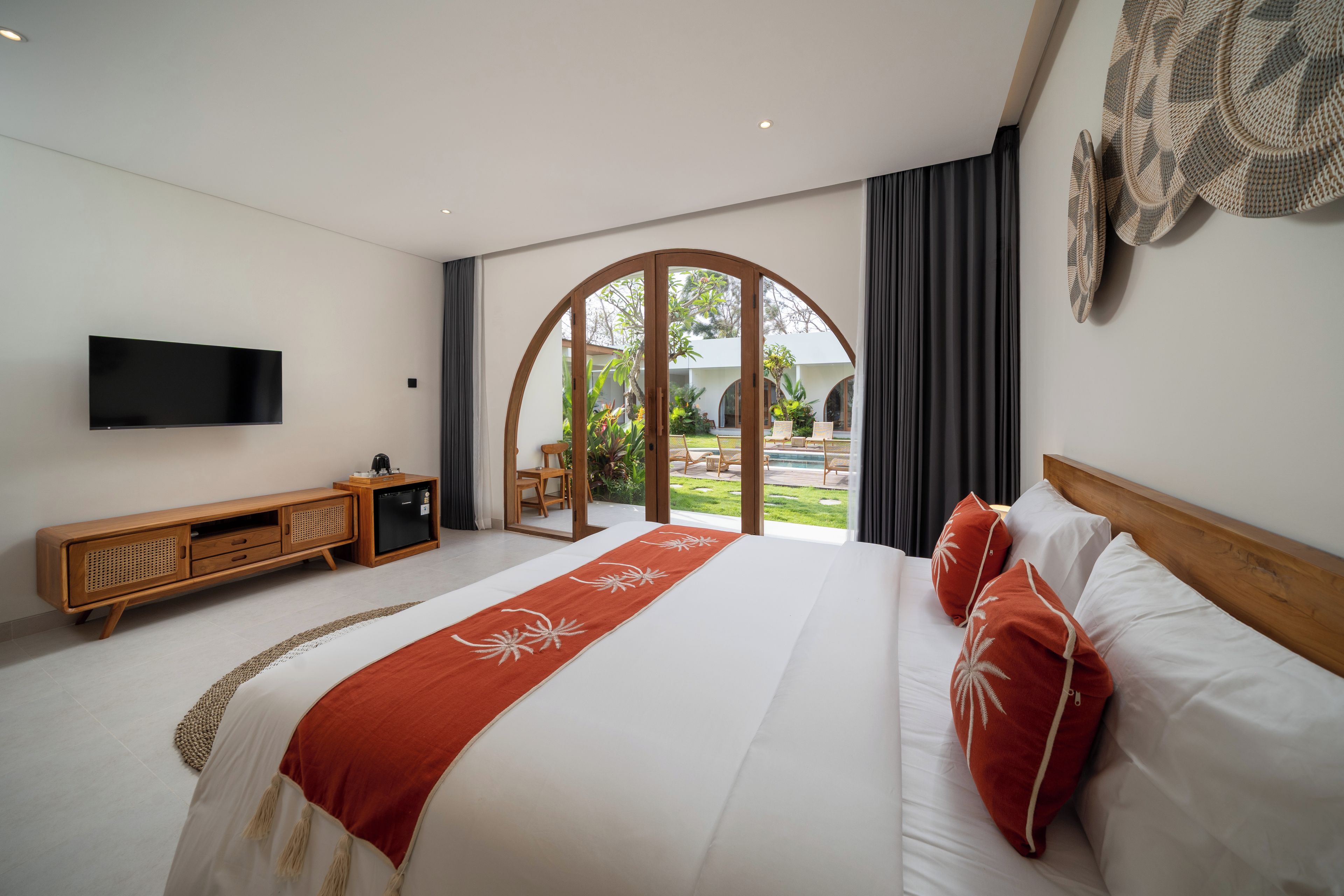 Habitación de hotel moderna con una cama grande, un televisor de pantalla plana, una consola de madera y vistas al área exterior.