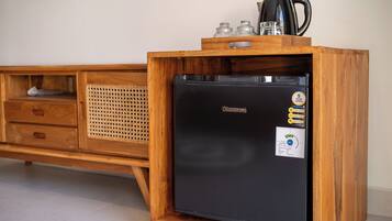 Un refrigerador negro compacto con gabinete de madera, una cesta tejida y una cafetera encima.