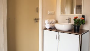 A bathroom with a white sink, a mirror, a towel rack, and a small potted plant. - Habba Dates Village (CHIKKABALLAPURA)