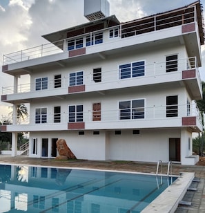 A multi-story building with a swimming pool in front.