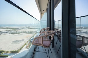 A balcony with wicker chairs and a view of a coastal landscape. - Bloomfields Studio in Soho Square B (Abu Dhabi)