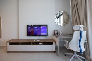 Una habitación moderna con televisión de pantalla plana en la pared, un escritorio con una silla y un espejo grande.