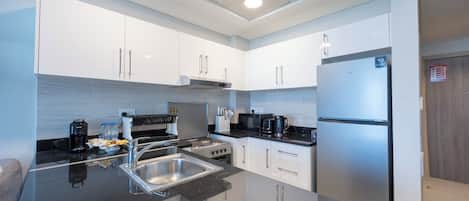 Una cocina moderna con armarios blancos, un refrigerador de acero inoxidable, una estufa y un lavamanos.