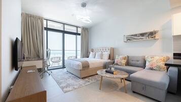 A modern hotel room with a bed, sofa, and a small coffee table.